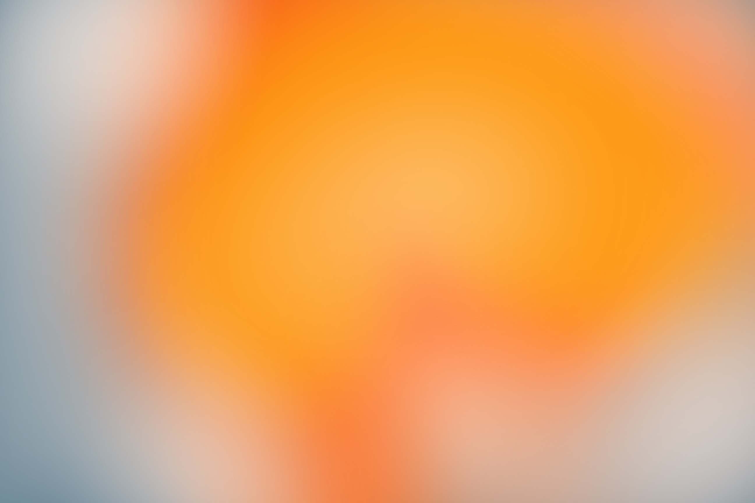 Abstracte, wazige achtergrond met een warm oranje-geel kleurverloop dat overgaat in een koel blauwgrijs.