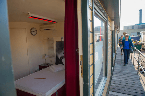 Kijk naar binnen door de deur: een bed met een rode lamp.