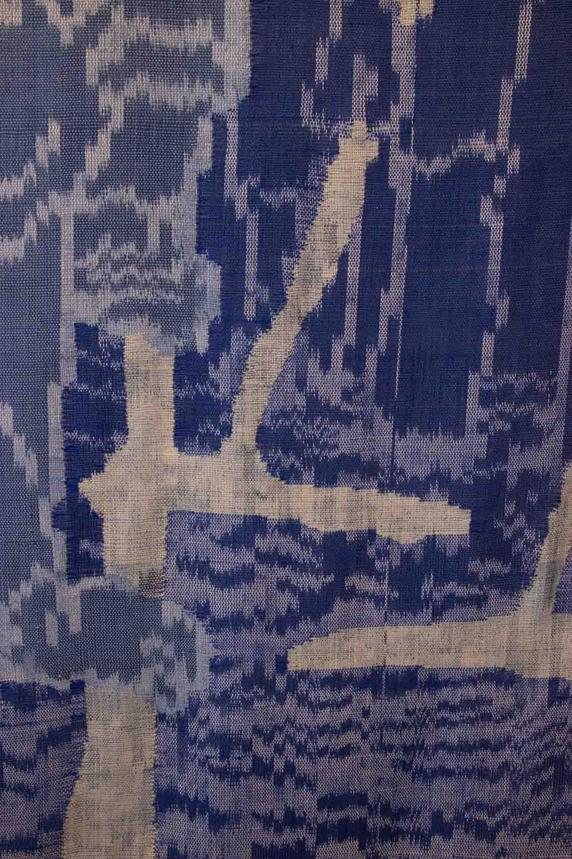 Een close-up van blauw-witte geweven stof met een abstract, onregelmatig patroon van lijnen en golven.