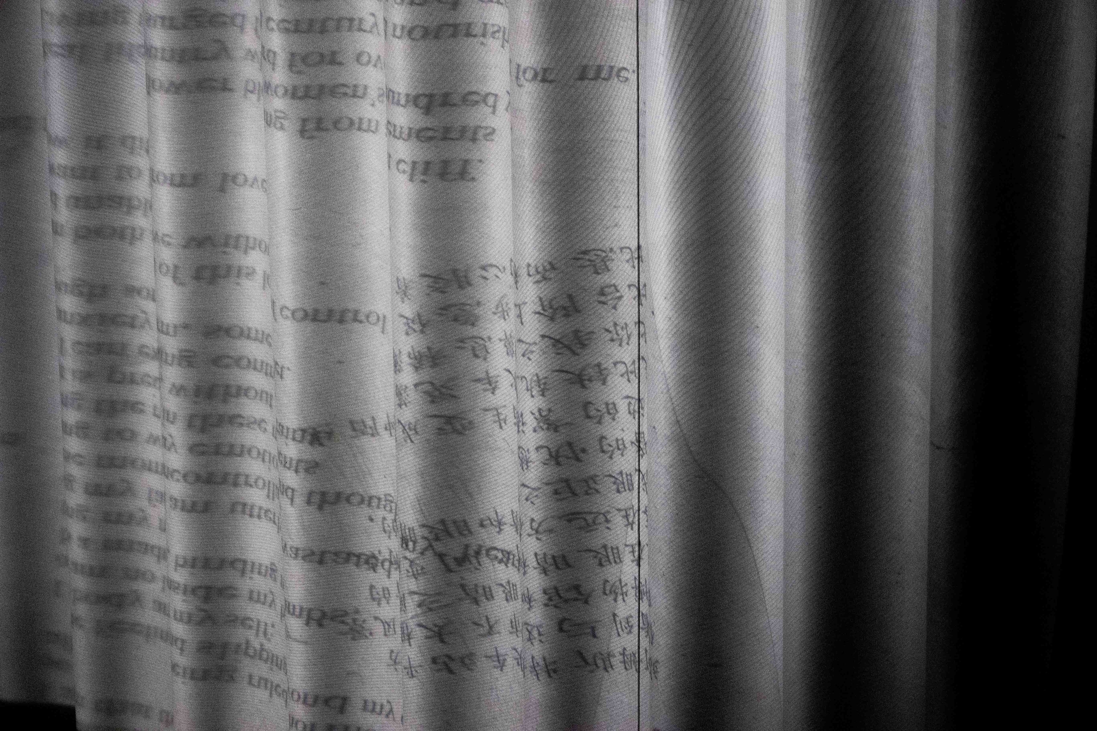 Mirrored English and Chinese text printed on a vertically folded, textured gray surface, fading to black on the right.
