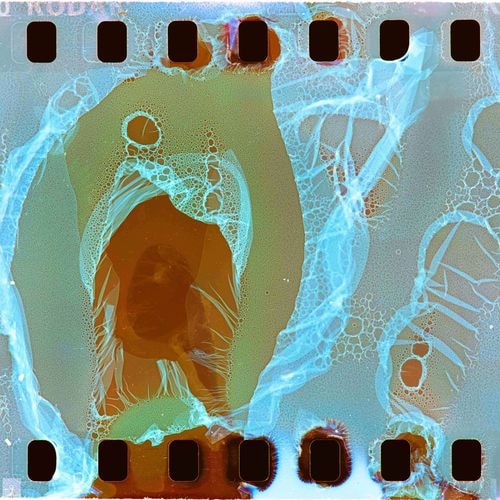 Beschadigde filmstrook (400 KOD) met blauw, webachtig patroon over oranjebruine en groengrijze lagen.